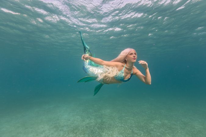 Blond fairytale female mermaid swimming underwater