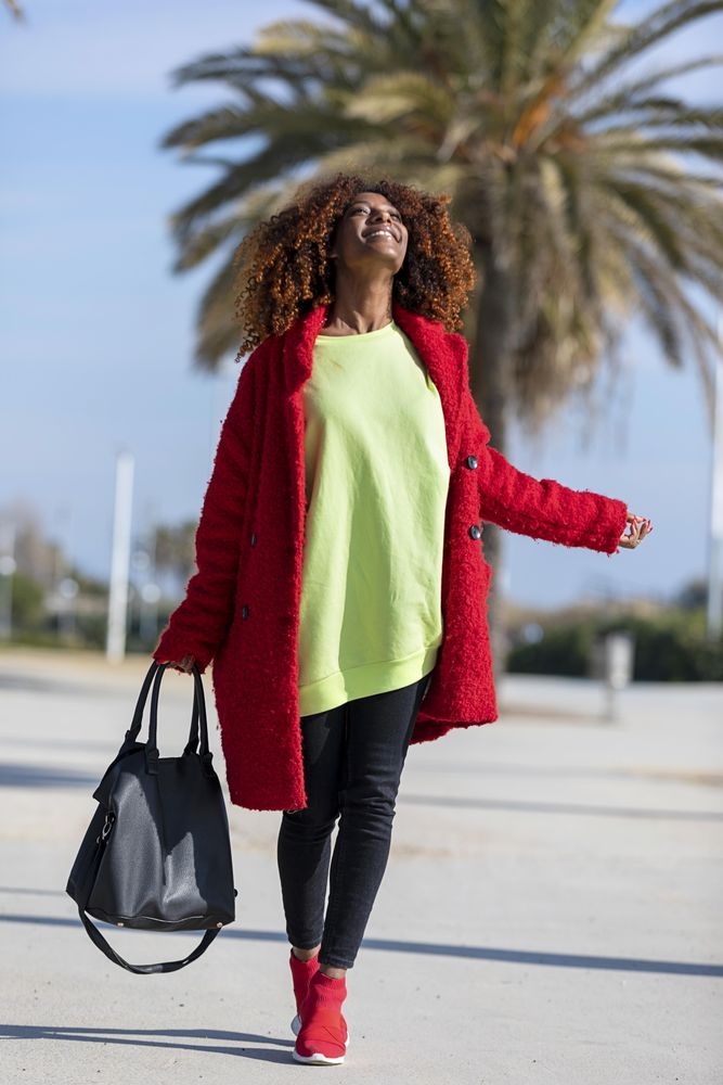 Female walking happily on street with palm trees on sunny day