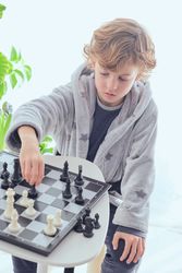 Focused preteen boy playing chess game on board