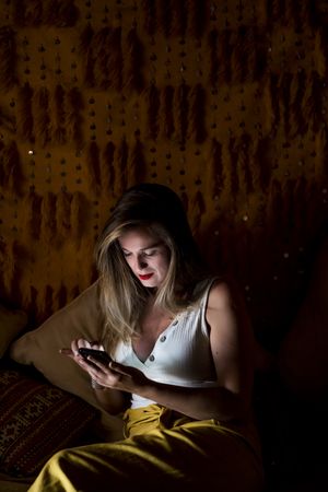 Smiling woman using smartphone in dark room