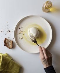 Crop hand taking cheese near bread and oil