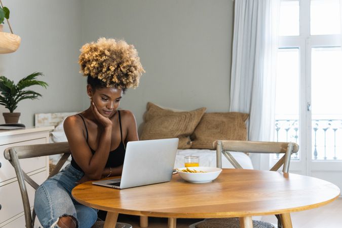Black woman with laptop sitting on chair during breakfast