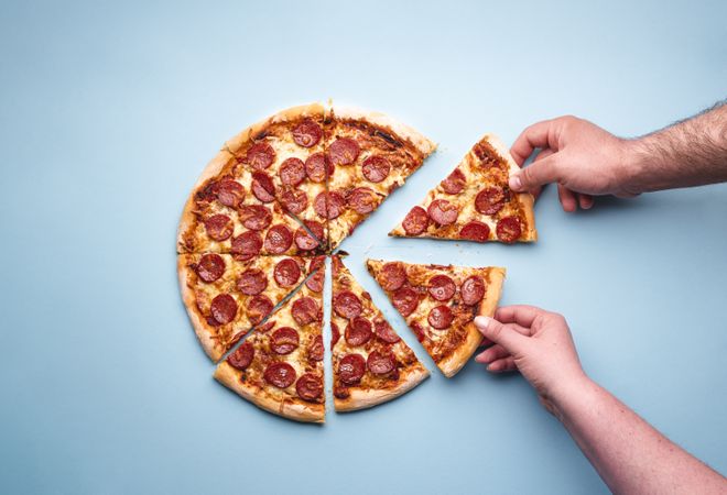 Two hands taking pizza slices