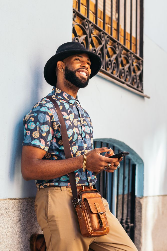 Stylish Black man using smartphone outdoors in the city