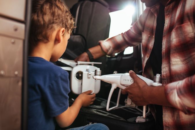 Adult male teaching young boy how to fly a drone