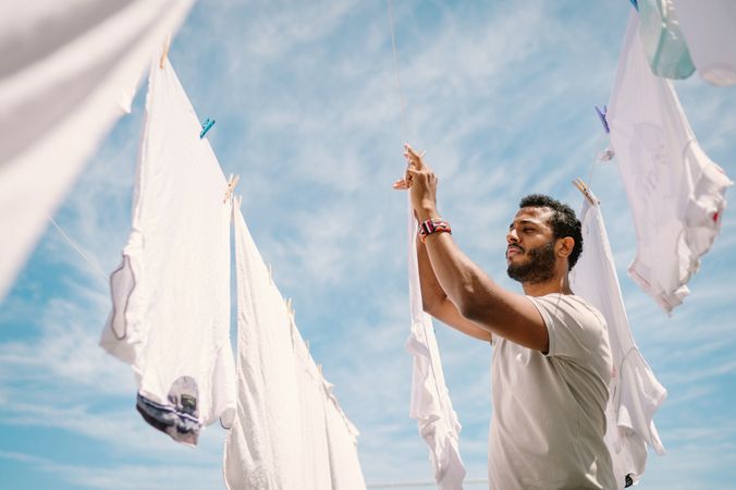 Diligent Black man hanging t-shirt on rope