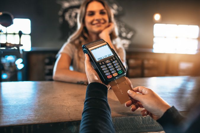 Close up of woman paying for bar tab with credit card machine