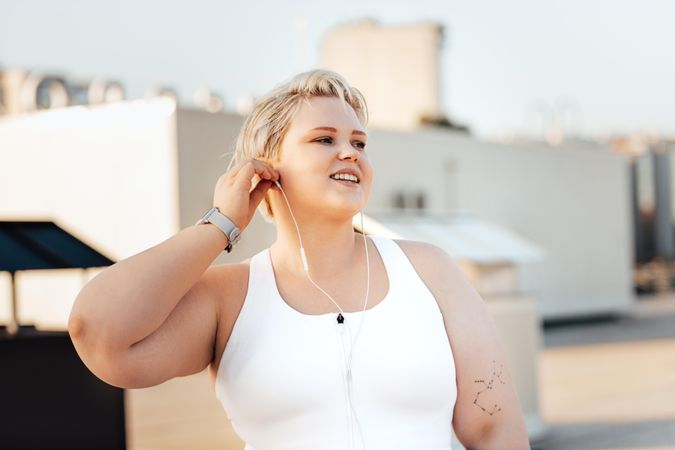 Woman in exercise gear and headphones getting ready to work out outside