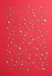 Scattered safety pins on red background