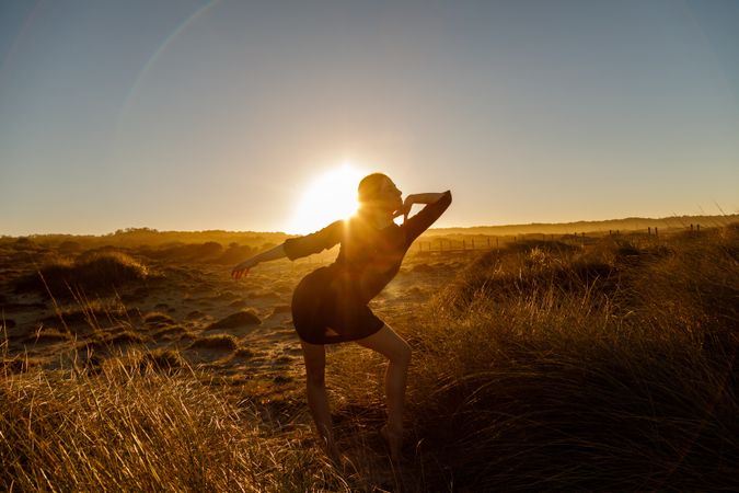 Woman posing between field at sunset