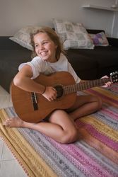 Barefoot girl playing guitar at home