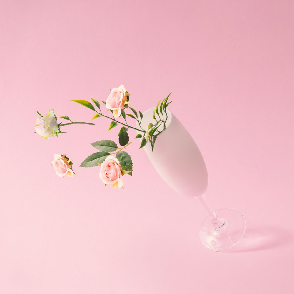 Champagne glass with spring flowers against pink background