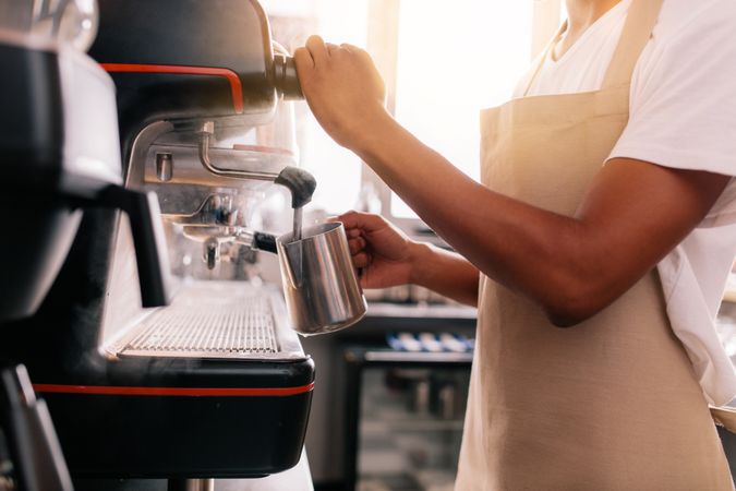 Close up of young man preparing coffee on machine
