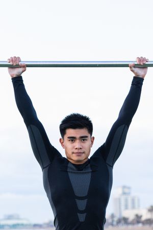 Asian sportsman exercising on monkey bars