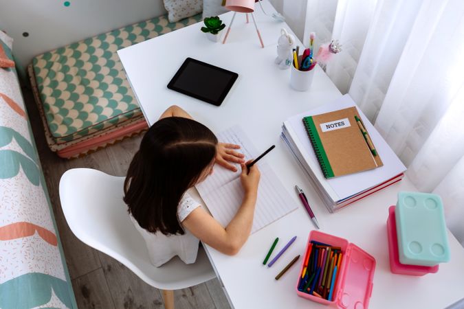 Girl doing homework in her bedroom