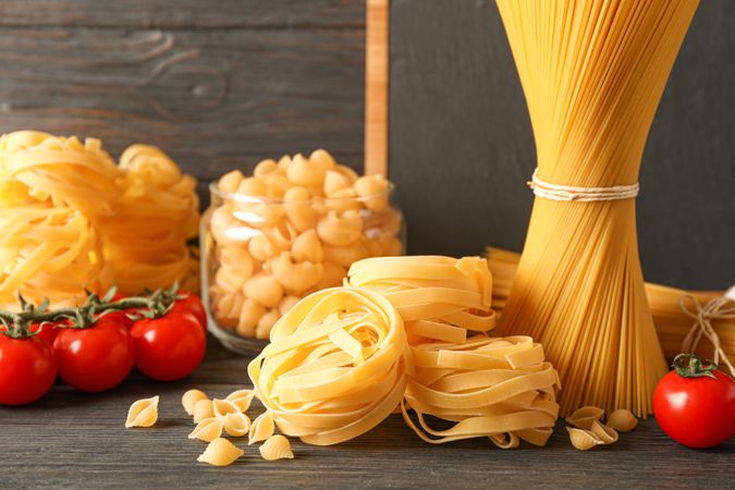 Composition with pasta cooking ingredients on wooden table, space for text