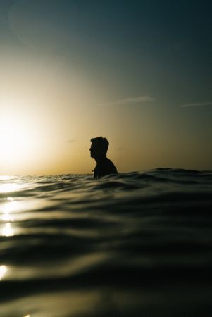 Silhouette of man in ocean water at dusk