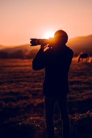 Man shooting on camera beautiful landscape between hills