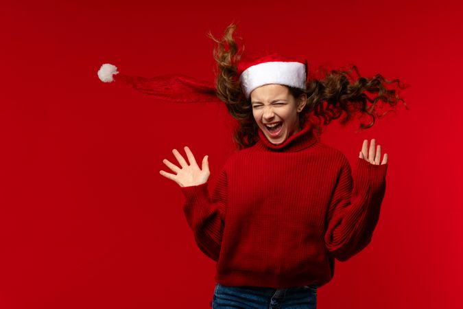Excited girl in Santa hat and red sweater laughs