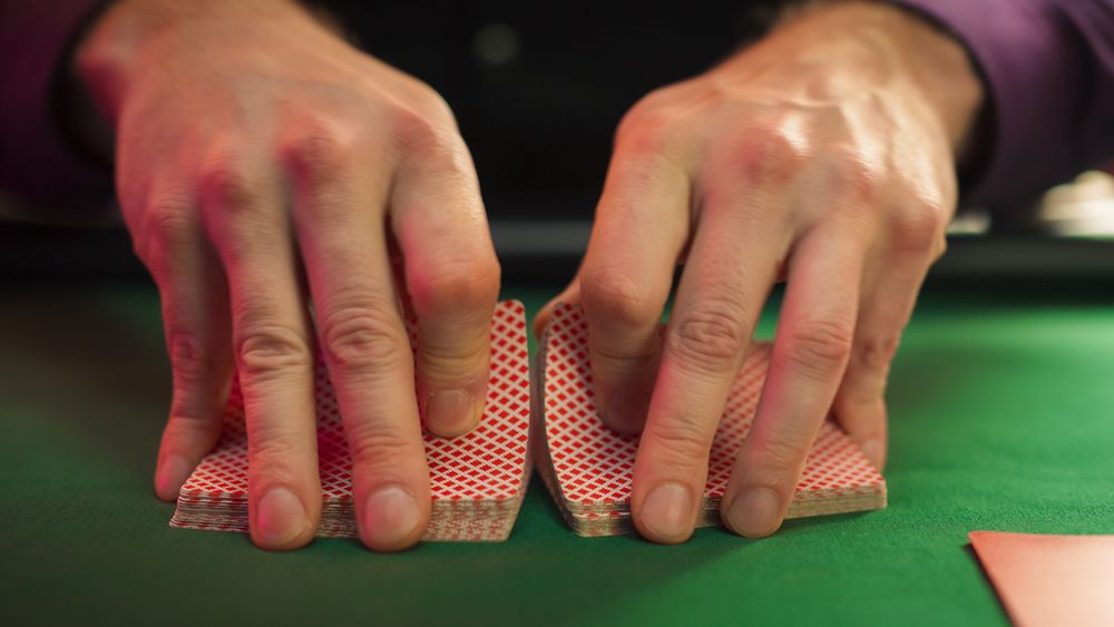Close Up On Hands Of Professional Poker Dealer Doing A Riffle Shuffle Of Playing Cards Before High Stakes Game In Luxurious Casino.