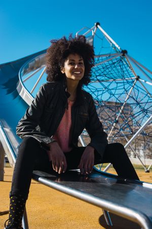 Woman with afro hair jumping down a slide.