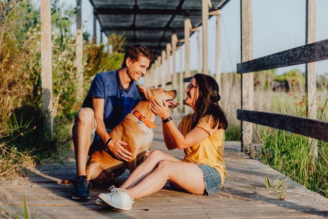 Happy adult couple having fun with dog at countryside