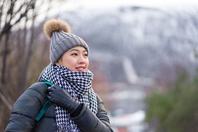 Asian female tourist in warm clothing at snowy nature