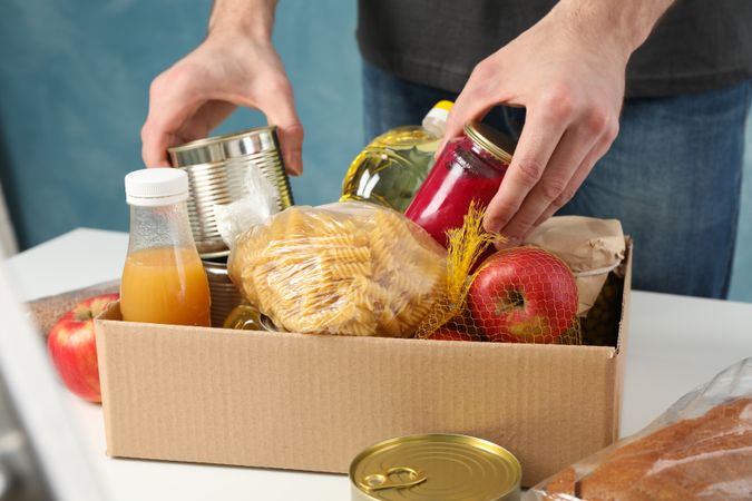 Young man puts groceries in donation box. Volunteer