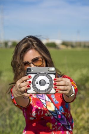 Woman showing photo camera in summer field