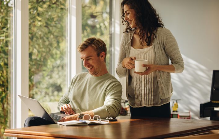 Husband and wife enjoying coffee and looking at laptop