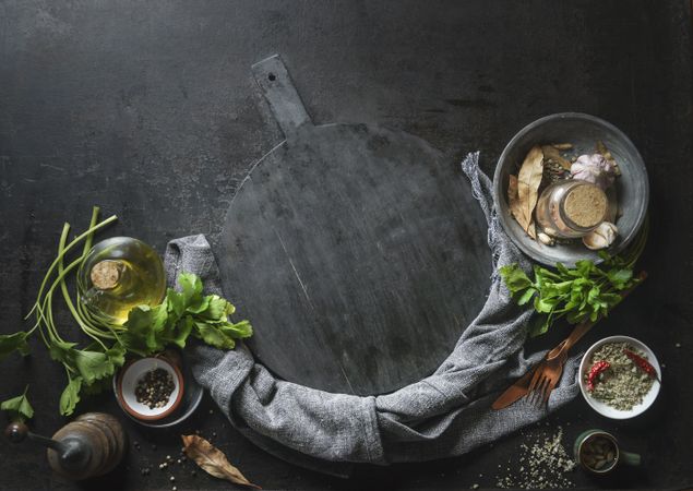 Kitchen flavor and seasoning ingredients with kitchen utensils  around empty cutting board. Top view. Frame