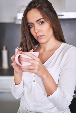 Woman drinking from cup in kitchen