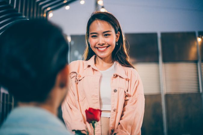 Smiling woman happy and receiving rose from boyfriend