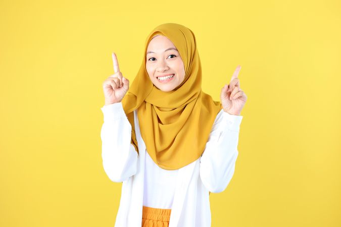Look There, Excited Muslim Woman in Hijab Pointing Upwards at Copy Space