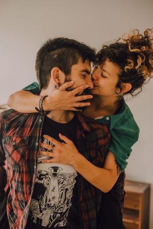 Loving hipster couple kissing and cuddling at home