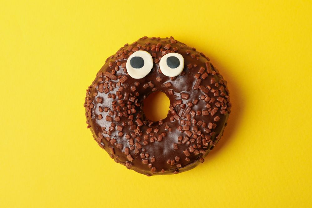 Tasty chocolate donut with eyes on yellow background