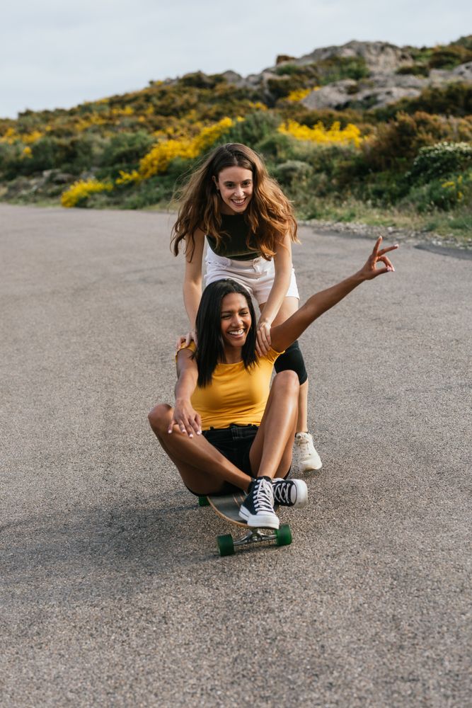 Happy diverse women riding longboard on road