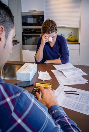 Woman with head down as her partner calculates bills