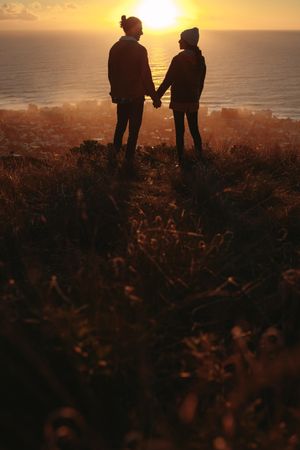 Love couple on peak looking at each other during sunset