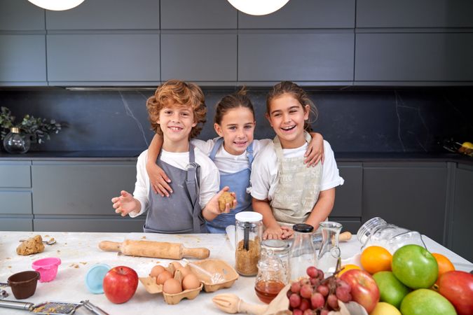 Cheerful children with dough in kitchen