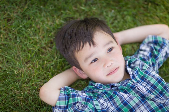 Boy Relaxing Outside On The Grass