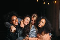 Multi-ethnic group of smiling women embracing outside