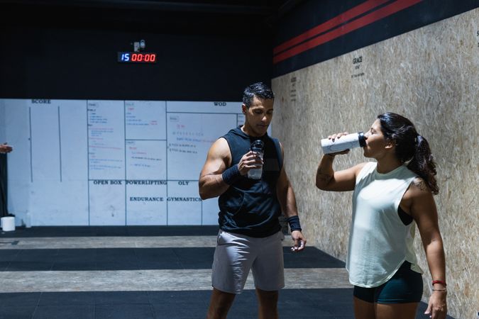 Hispanic couple drinking water in gym