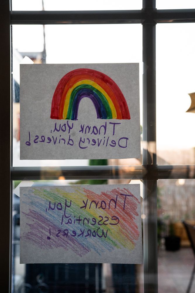 Reverse view of two handmade signs from within a house thanking essential workers