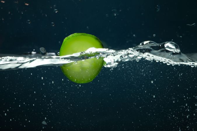 Side view of water wave on dark background with cucumber