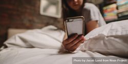 Young woman using mobile phone while sitting on bed 5pOQ80
