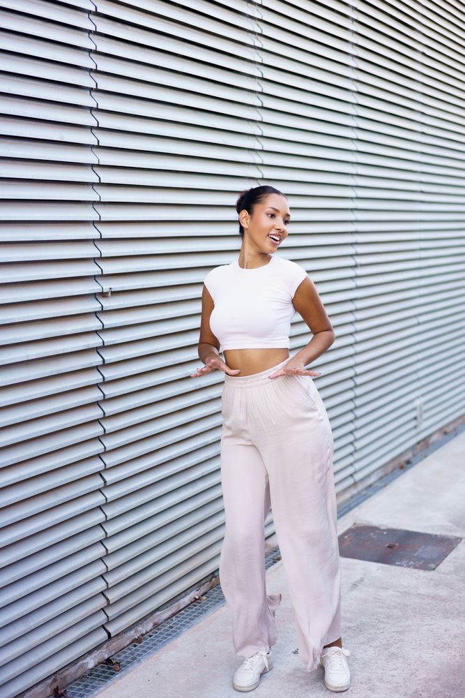 A stylish young woman poses confidently against a contemporary architectural background