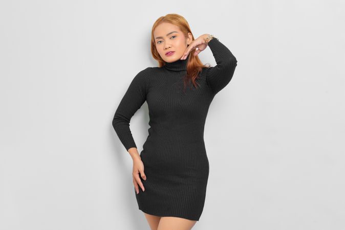 Serious Asian woman with red hair and turtle neck dress in studio