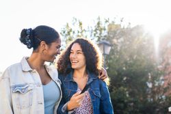 Black Latina friends using a smartphone in the park.