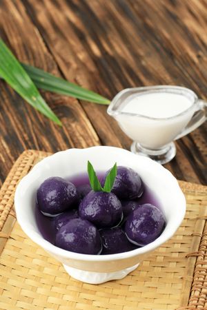 Bowl of purple sweet potato balls with palm sugar served with coconut milk sauce